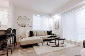 Edmonton apartment for rent - A modern living room with a white sofa, a black table, and a large window.