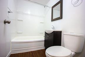 Edmonton apartment for rent - A white toilet sits next to a white bathtub in a bathroom.