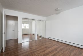 Edmonton apartment for rent - A room with white walls and wooden floors with a sliding glass door.