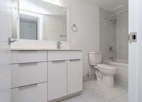 Edmonton apartment for rent - A white bathroom with a toilet, sink, and mirror.