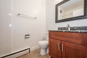 Edmonton apartment for rent - A bathroom with a toilet, sink, and a mirror.