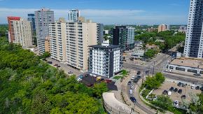 Edmonton apartment for rent - A cityscape with a mix of residential and commercial buildings, surrounded by greenery and roads with vehicles.
