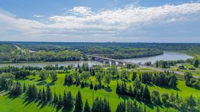 Edmonton apartment for rent - A bridge spans a river in a lush green landscape.