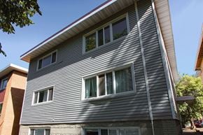 Edmonton apartment for rent - A grey house with a red brick building behind it.