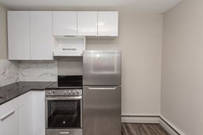 Edmonton apartment for rent - A modern kitchen with a stainless steel refrigerator, oven, and range hood.