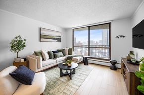 Edmonton apartment for rent - A living room with a couch, a chair, a coffee table, and a large window.