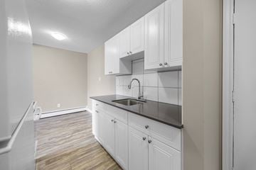Edmonton apartment for rent - A kitchen with white cabinets and a black countertop.