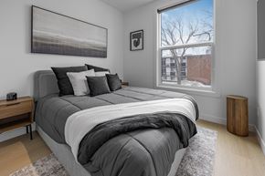 Edmonton apartment for rent - A bedroom with a large bed and a window showing a building outside.