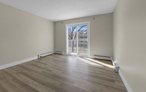 Edmonton apartment for rent - A room with light wood flooring and a white door leading to a balcony.