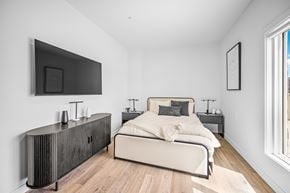 Edmonton apartment for rent - A modern bedroom with a large bed and a flat screen TV mounted on the wall.