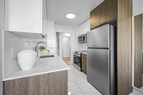 Edmonton apartment for rent - A modern kitchen with a stainless steel refrigerator and wooden cabinets.