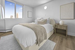 Edmonton apartment for rent - A bedroom with a large bed and a window overlooking the city.