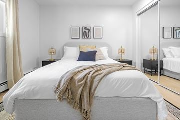 Edmonton apartment for rent - A bedroom with a large bed covered in a white duvet and a beige throw.