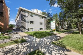 Edmonton apartment for rent - A sunny day at a residential area with apartment buildings and a sign that says "Welcome to Maple Grove".