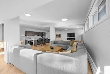 Edmonton apartment for rent - A modern living room with a grey sofa and a kitchen in the background.