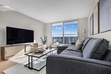 Edmonton apartment for rent - A modern living room with a grey couch and a flat screen TV.