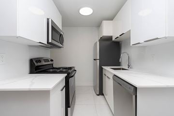 Edmonton apartment for rent - A white kitchen with black appliances and a white counter top.