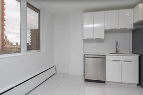 Edmonton apartment for rent - A kitchen with white cabinets and a window overlooking a cityscape.
