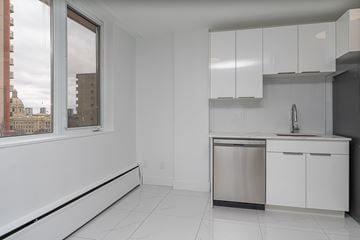 Edmonton apartment for rent - A kitchen with white cabinets and a window overlooking a cityscape.