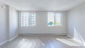 Edmonton apartment for rent - A large empty room with a window overlooking a cityscape.