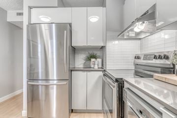 Edmonton apartment for rent - A modern kitchen with a stainless steel refrigerator and a range hood.