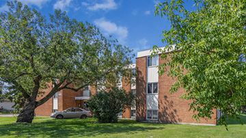 Edmonton apartment for rent - A tree in front of a red brick building.