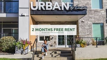 Edmonton apartment for rent - A person is sitting on the steps of a building with a sign that reads "URBAN 2 MONTHS FREE RENT".