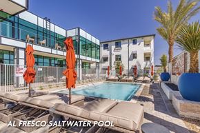 Las Vegas apartment for rent - A saltwater pool is surrounded by a patio with chairs and umbrellas.