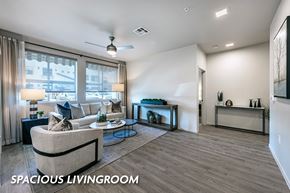 Las Vegas apartment for rent - A spacious living room with a couch, a coffee table, and a window with curtains.