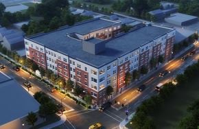 Orange apartment for rent - A modern apartment building is shown at night with street lights and cars.
