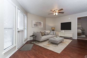 Bossier City apartment for rent - A living room with a grey couch and a white wall.