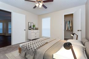 Bossier City apartment for rent - A bedroom with a bed, a couch, a ceiling fan, and a window with blinds.