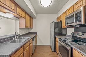 Bossier City apartment for rent - A kitchen with wooden cabinets and black appliances.