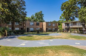Shreveport apartment for rent - A playground area with a roundabout and a building in the background.