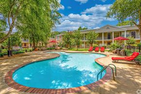 Shreveport apartment for rent - A swimming pool surrounded by a red brick border with a building in the background.