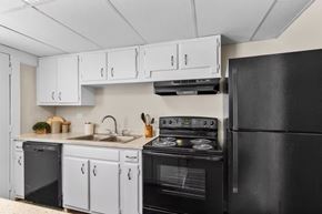 Shreveport apartment for rent - A black refrigerator is on the right side of a kitchen with white cabinets.