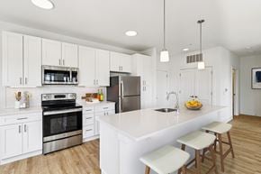 Blue Ash apartment for rent - A modern kitchen with white cabinets and a large island.