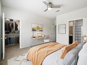 Cary apartment for rent - A bedroom with a bed, a desk, a chair, a closet, and a ceiling fan.