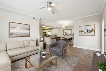 Atlanta apartment for rent - A living room with a beige couch, a grey armchair, a glass coffee table, and a ceiling fan.