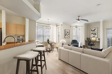 Cincinnati apartment for rent - A modern kitchen with a bar area and a living room area with a couch and chairs.