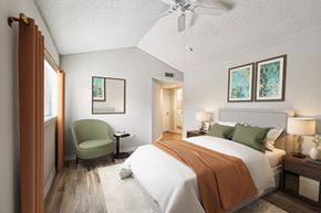 Coral Springs apartment for rent - A bedroom with a large bed and a green chair.