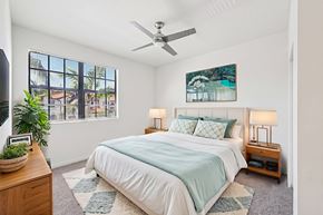 Miramar apartment for rent - A bedroom with a bed, a ceiling fan, and a window with a view of a cityscape.
