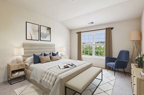 Miamisburg apartment for rent - A bedroom with a large bed, a chair, and a window with blinds.