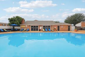 Cincinnati apartment for rent - A large swimming pool in front of a building with a blue sky and clouds in the background.