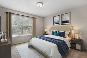 Cincinnati apartment for rent - A bedroom with a large bed and a window with blinds.