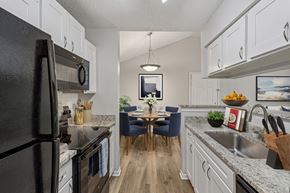 Cincinnati apartment for rent - A kitchen with a black refrigerator and a dining table with chairs.