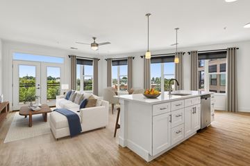 Blue Ash apartment for rent - A modern living room with a white sofa and a kitchen area in the background.