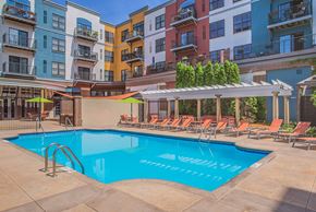 St. Louis Park apartment for rent - A pool surrounded by chairs and umbrellas in front of apartment buildings.