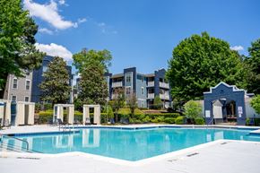 Huntersville apartment for rent - A swimming pool in front of a building with trees around.