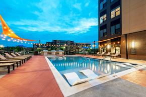 Blue Ash apartment for rent - A pool area with a long row of sun loungers and a building in the background.